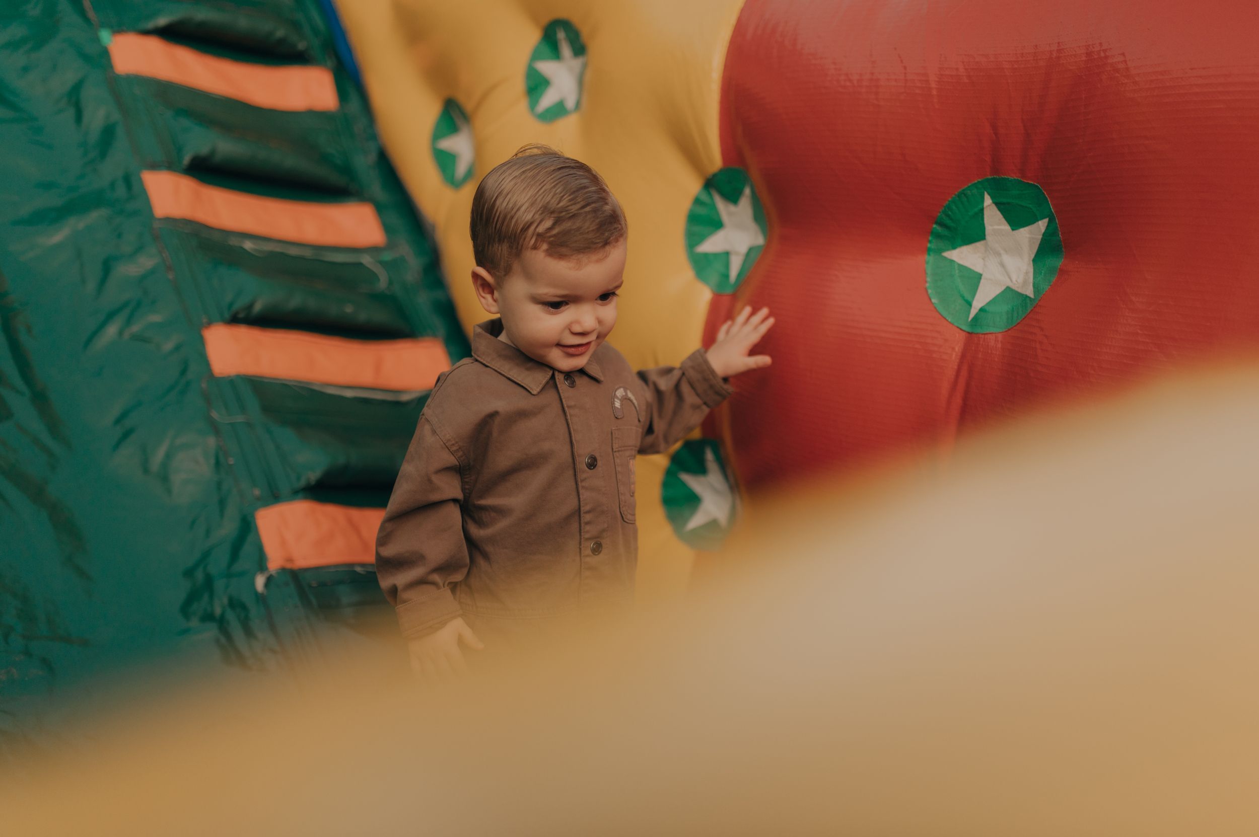 A young child stands in front of colorful decorative backdrop with stars and patterns.