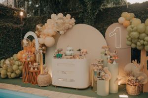 Elegant party decoration with neutral balloon arch and dessert table setup.