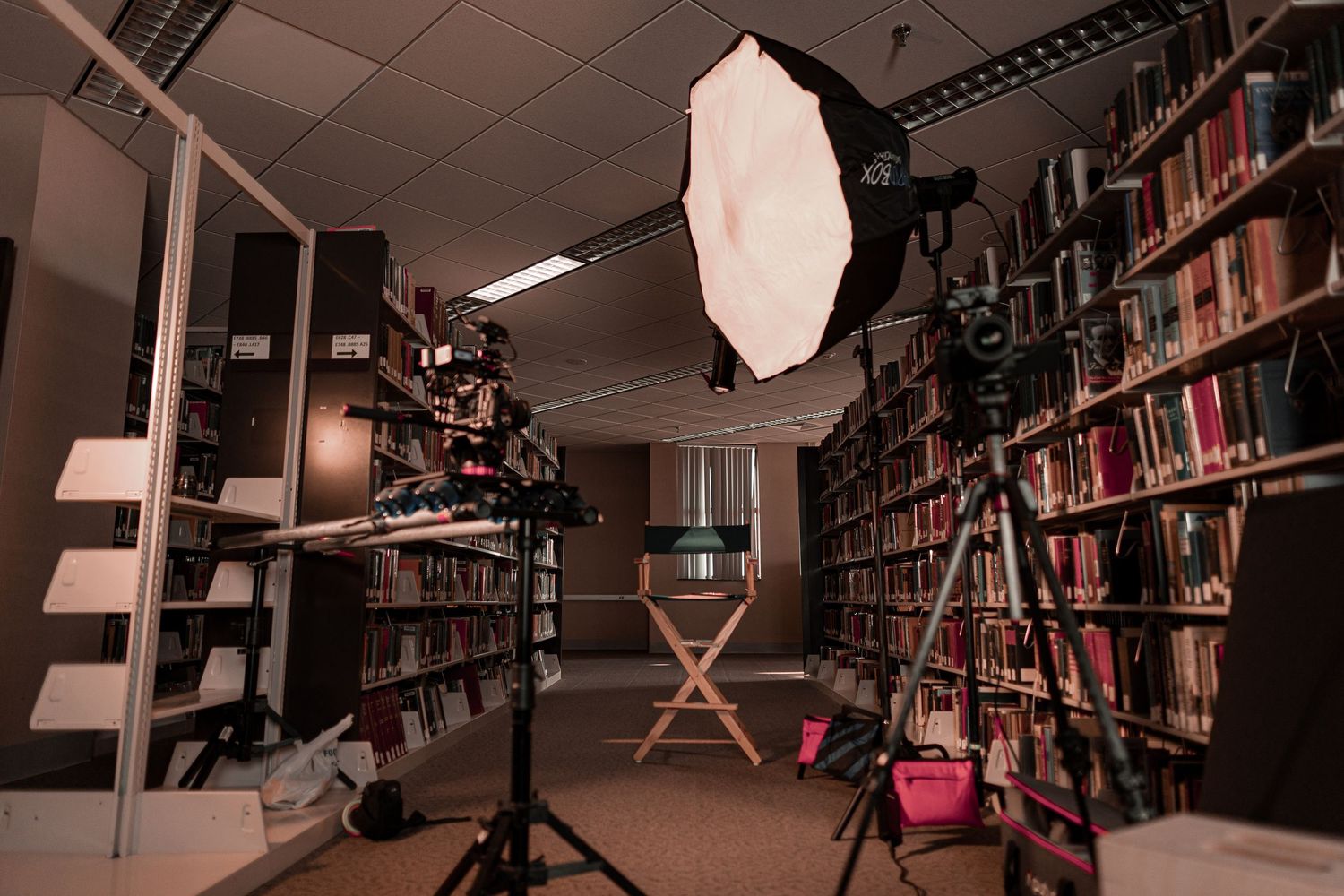 Professional photography setup in a library with lighting equipment and bookshelves.