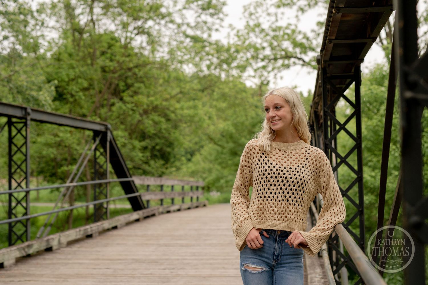 Fashion portrait of someone wearing a beige knit sweater on a rustic wooden bridge.