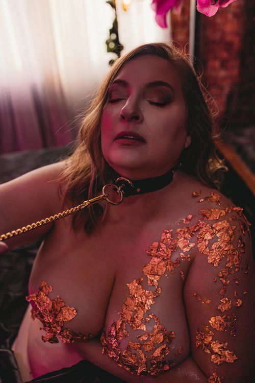 Intimate boudoir photo with copper colored sparkly flower appliques in warm moody lighting.