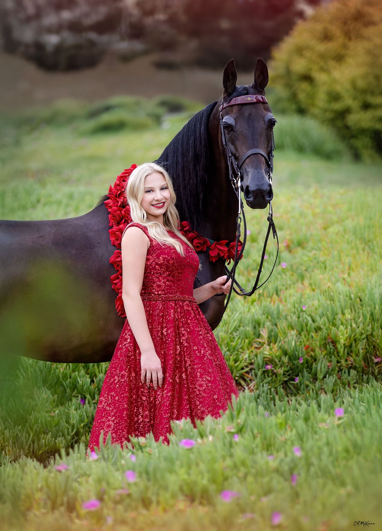Beautiful girl in red dress standing with her black English Pleasure mare who is wearing National Championship roses