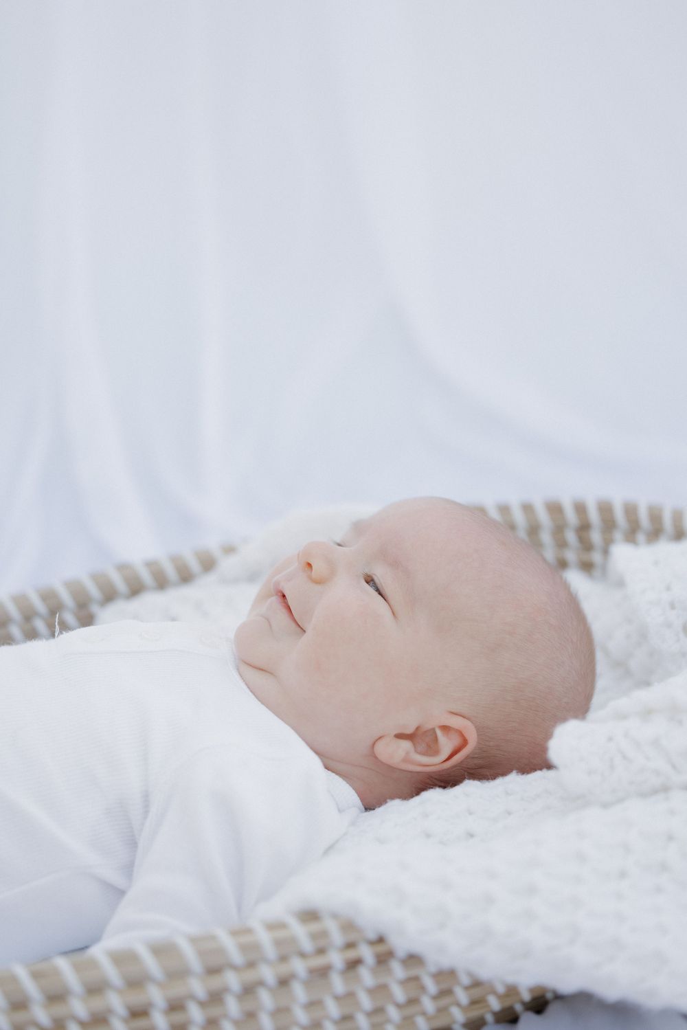 A peaceful sleeping baby rests on soft white bedding with a knitted blanket. location shepparton