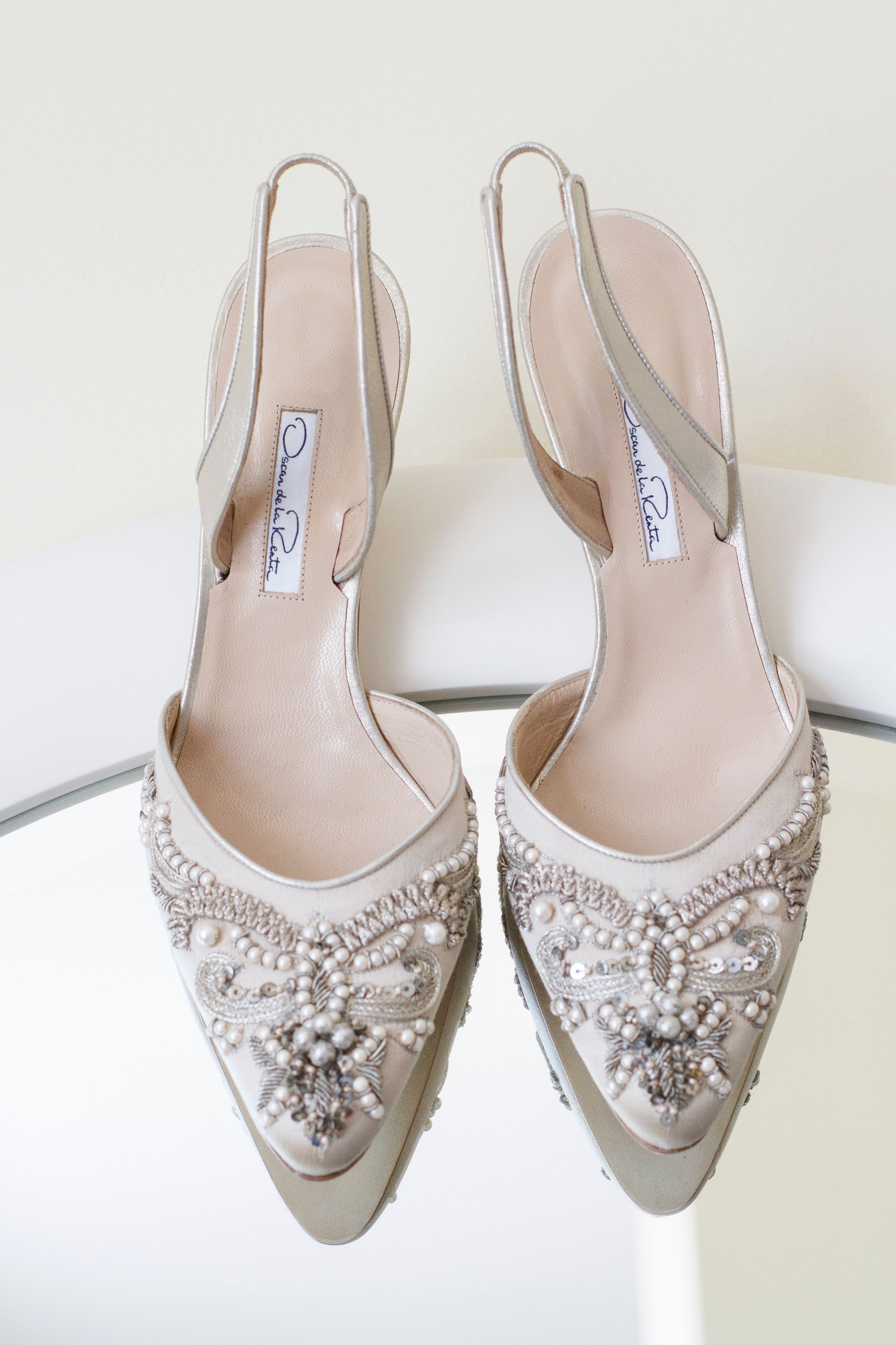 Oscar de la Renta bridal slingback heels with pearl and crystal embellishments on mirrored surface.
