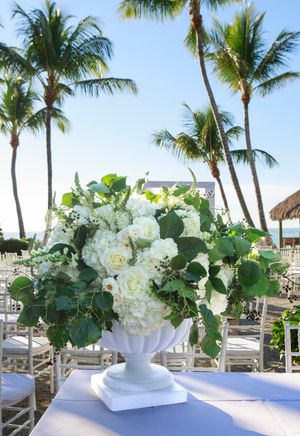 Lush white rose and hydrangea floral arrangement at tropical outdoor wedding ceremony.