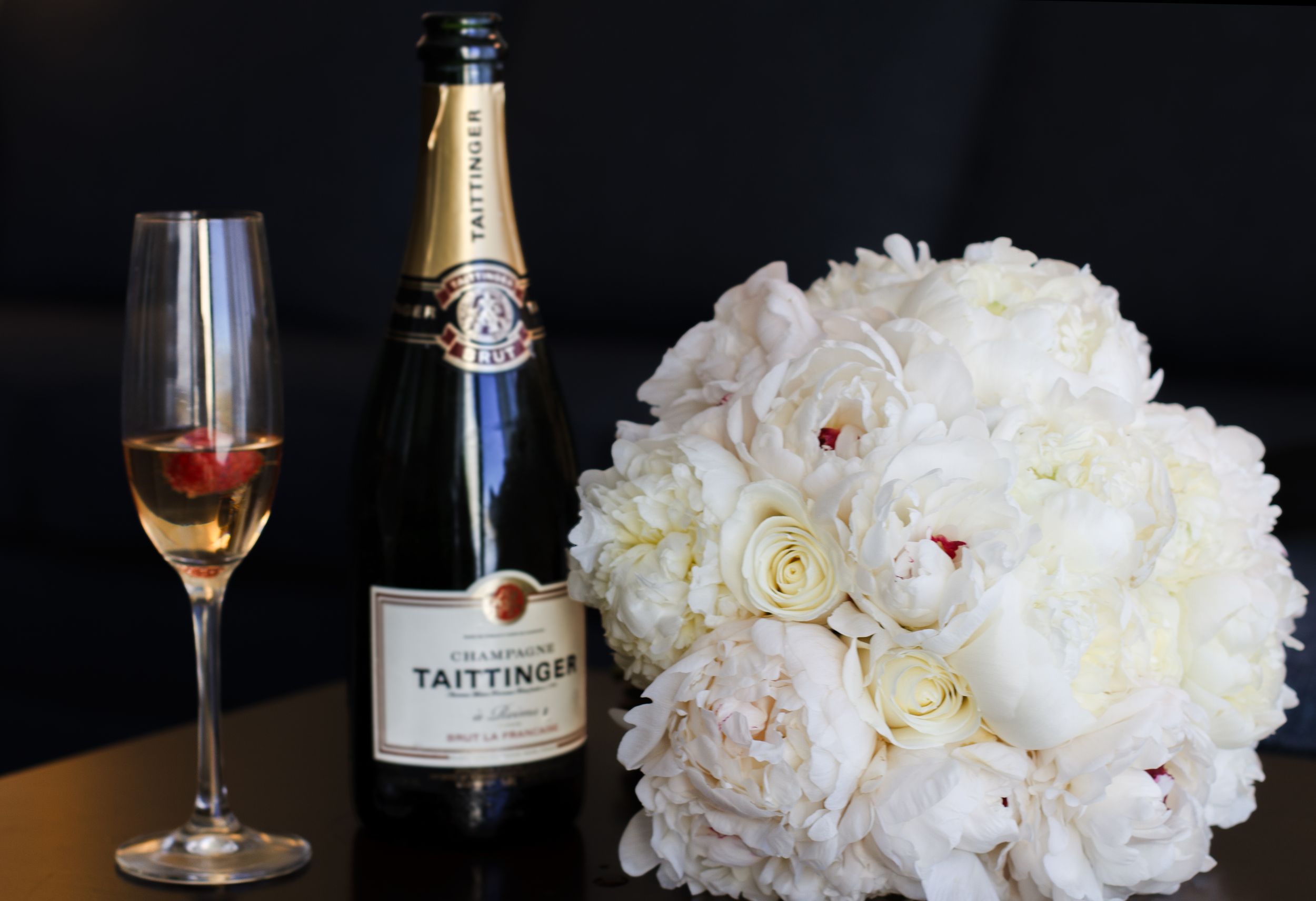 Bottle of Taittinger champagne with flute and white peony bridal bouquet. Naples