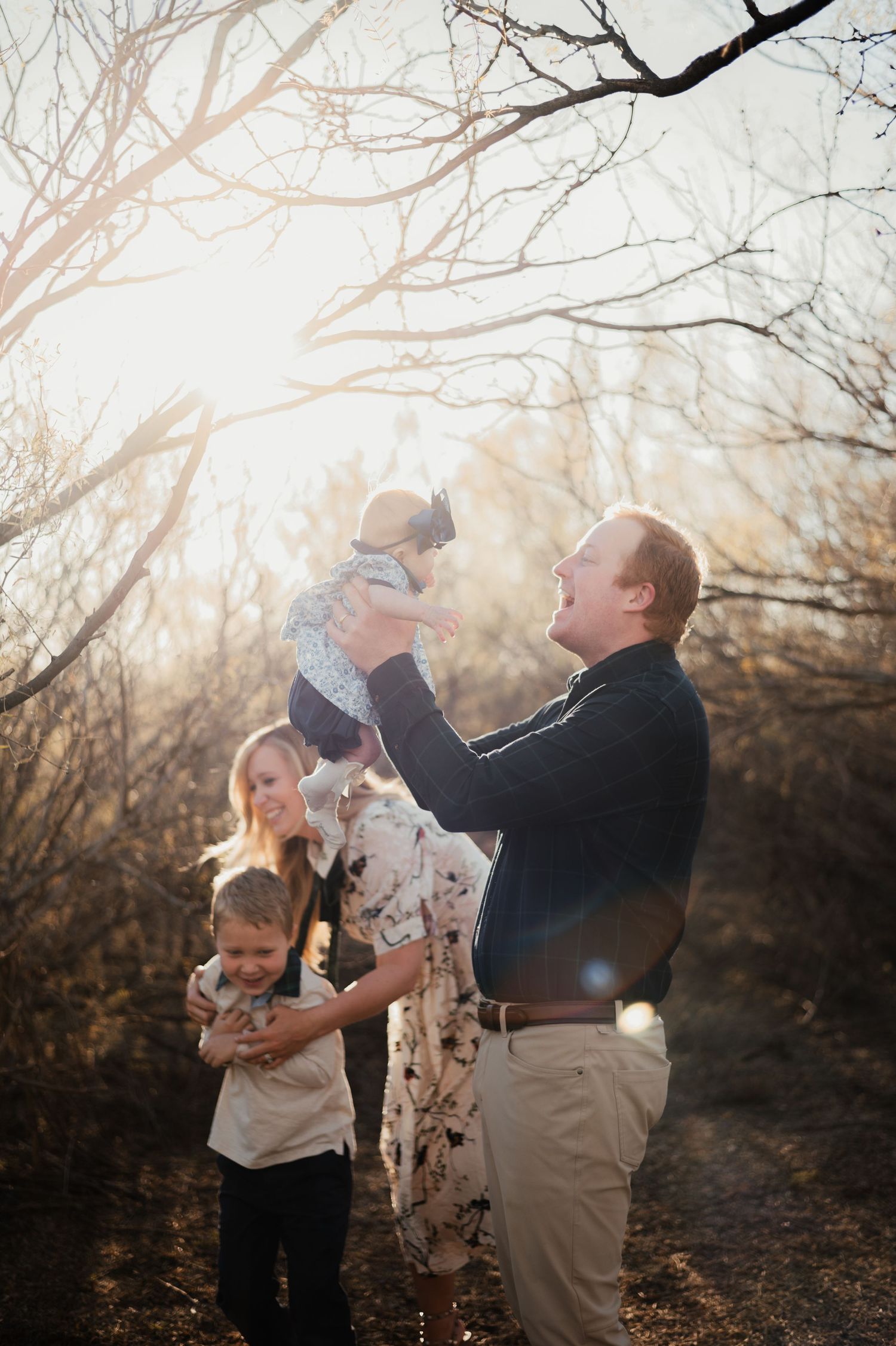 Heartwarming family moment captured in sunlit wooded setting.