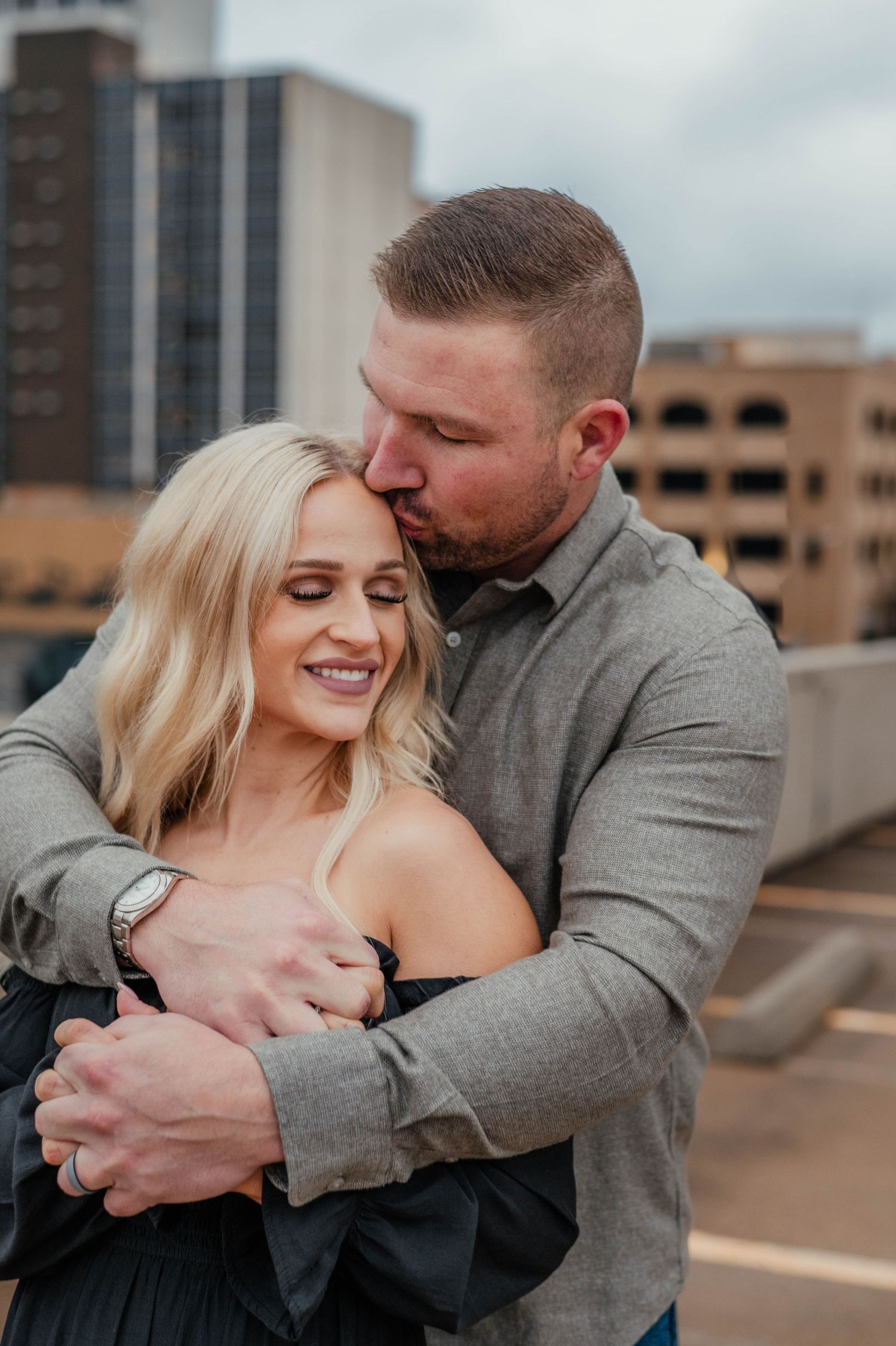 An intimate urban rooftop moment with couple embracing against city backdrop.