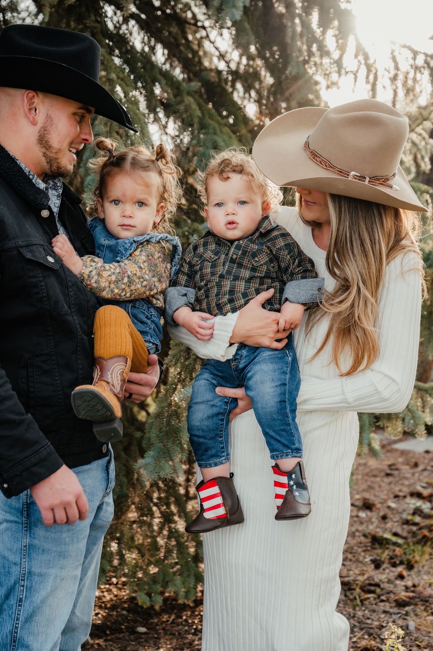 Family wearing western hats poses together outdoors with two small children in casual clothing.