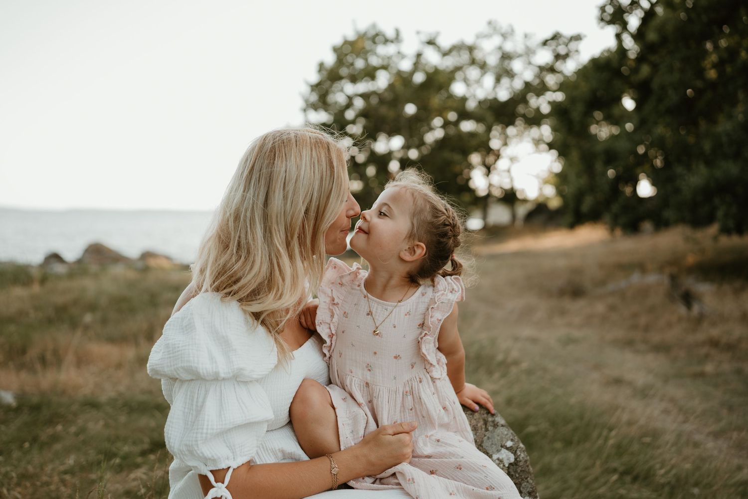 Family sharing playful moments on blanket by waterfront during golden hour.