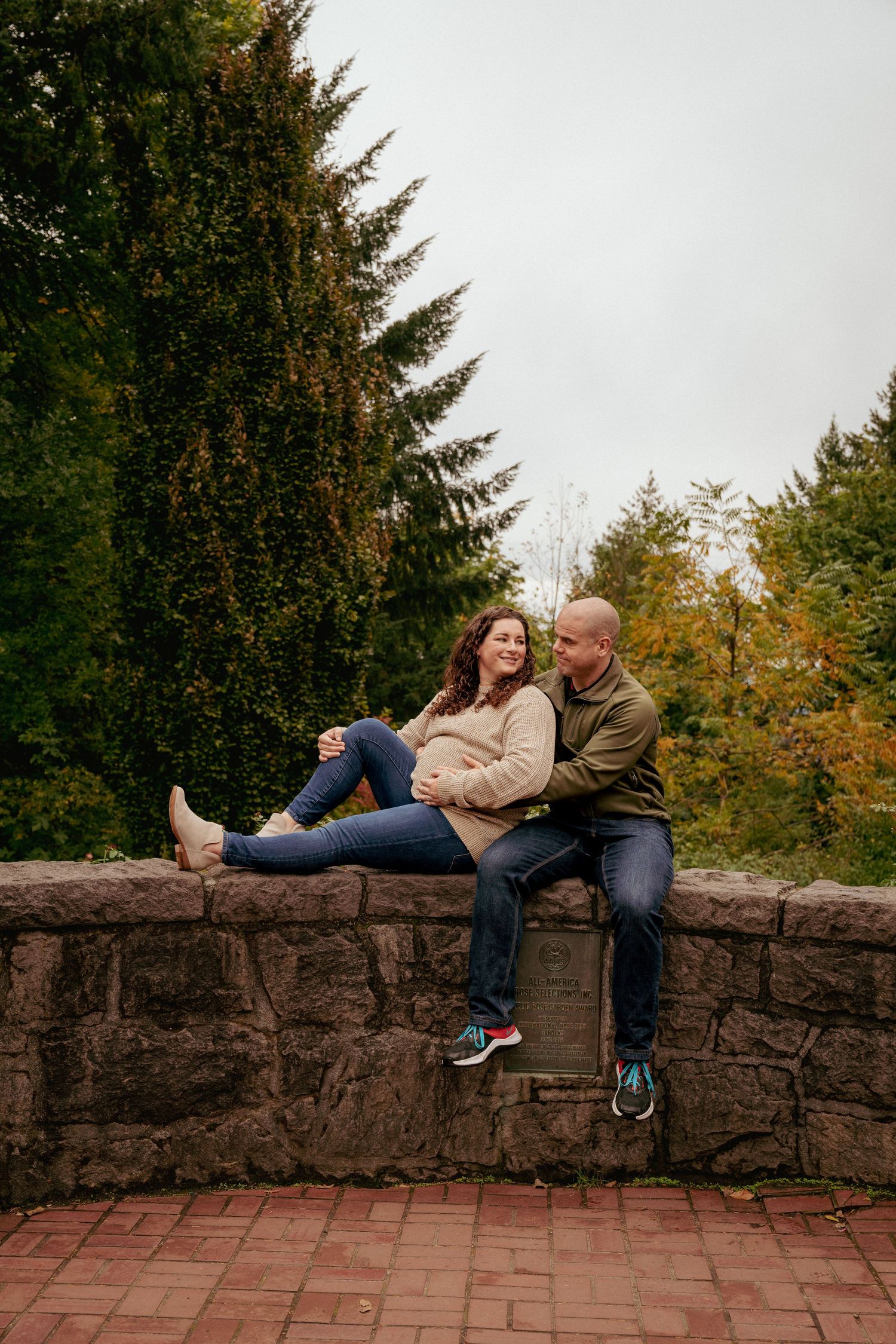 Casual maternity photo on stone wall in forest, Portland metro maternity portraits, fall vibes in Oregon.