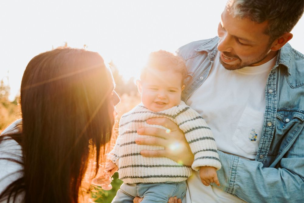Family sharing tender moment in golden sunlight outdoors during sunset photoshoot.