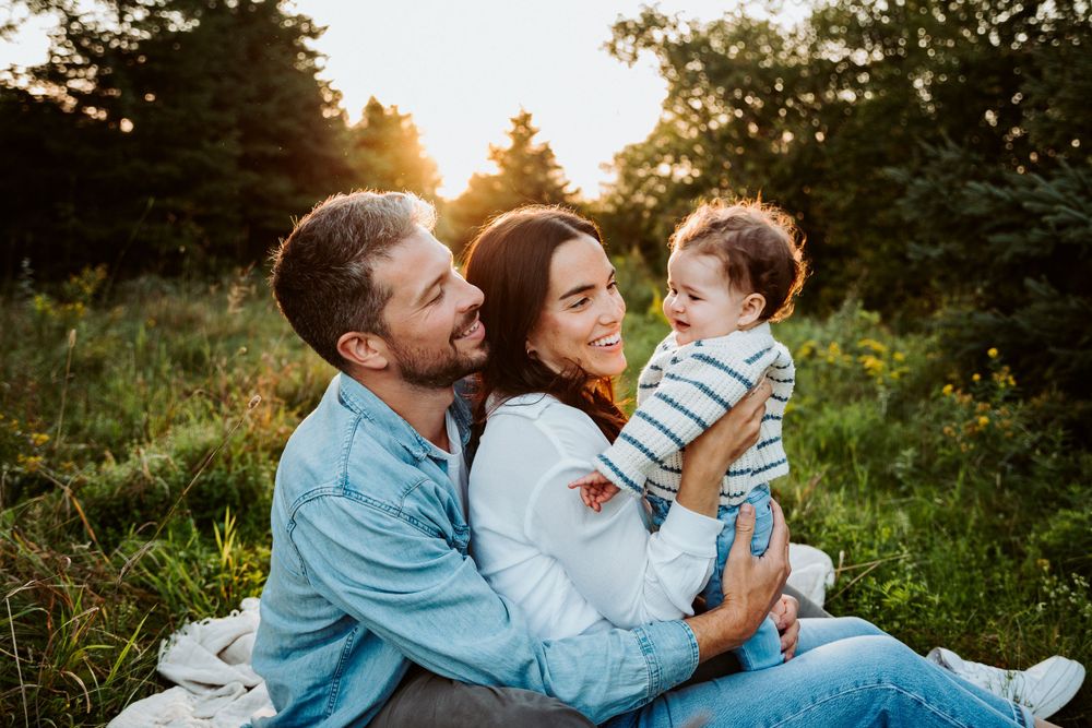 Family enjoying outdoor photo session in field during golden hour sunset.
