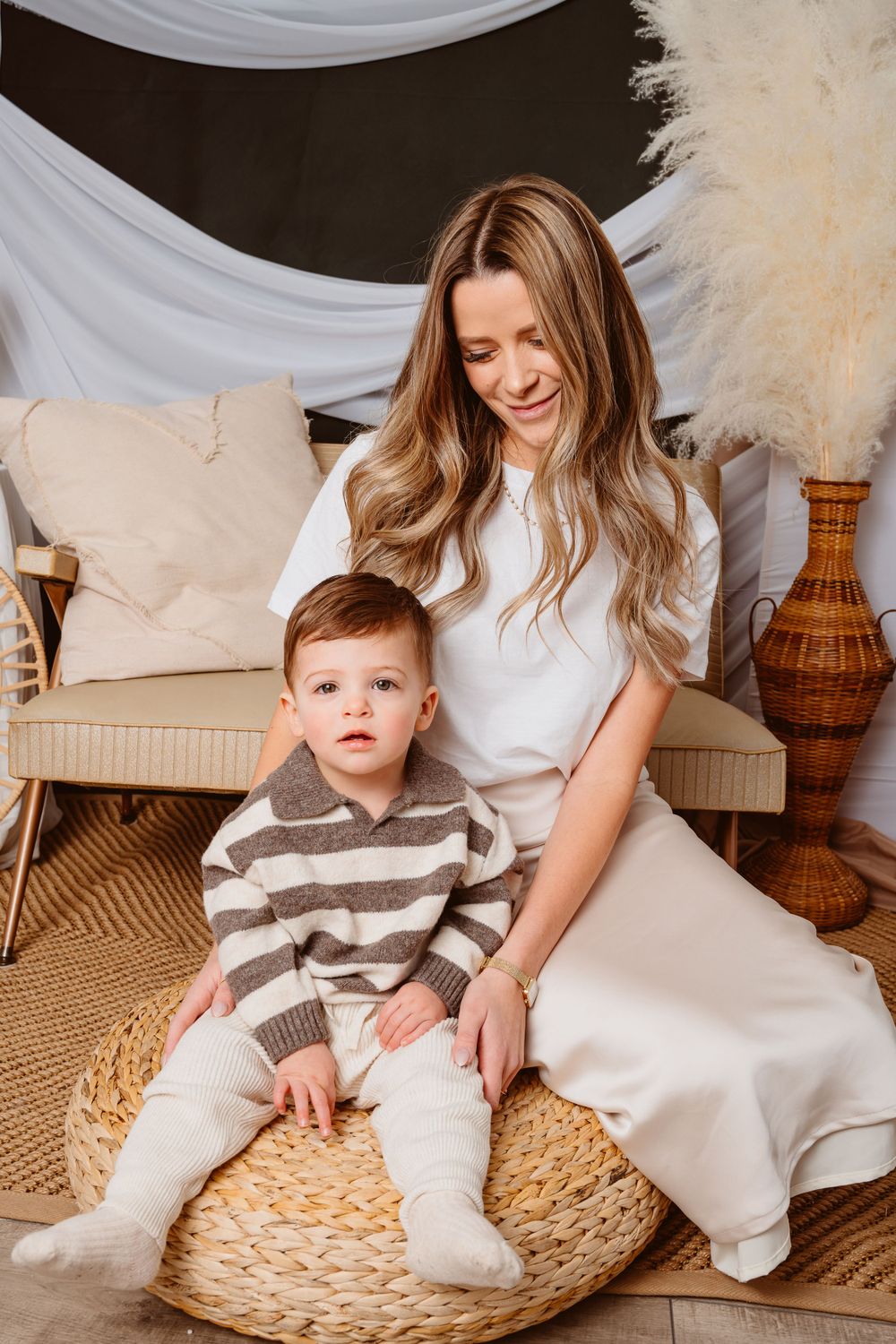 Cozy family scene with baby in striped outfit sitting on woven rug with light decor.
