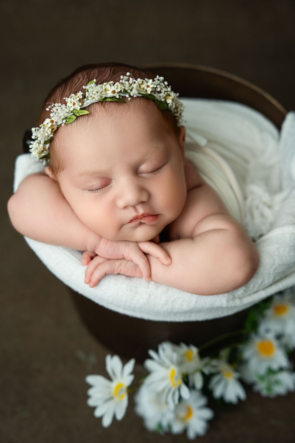 Sweet newborn portrait with floral crown in brown bowl with daisies.