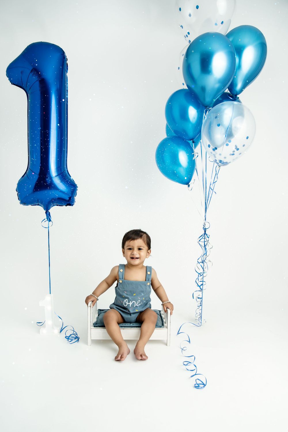 First birthday photoshoot with blue number one balloon and festive decorations.