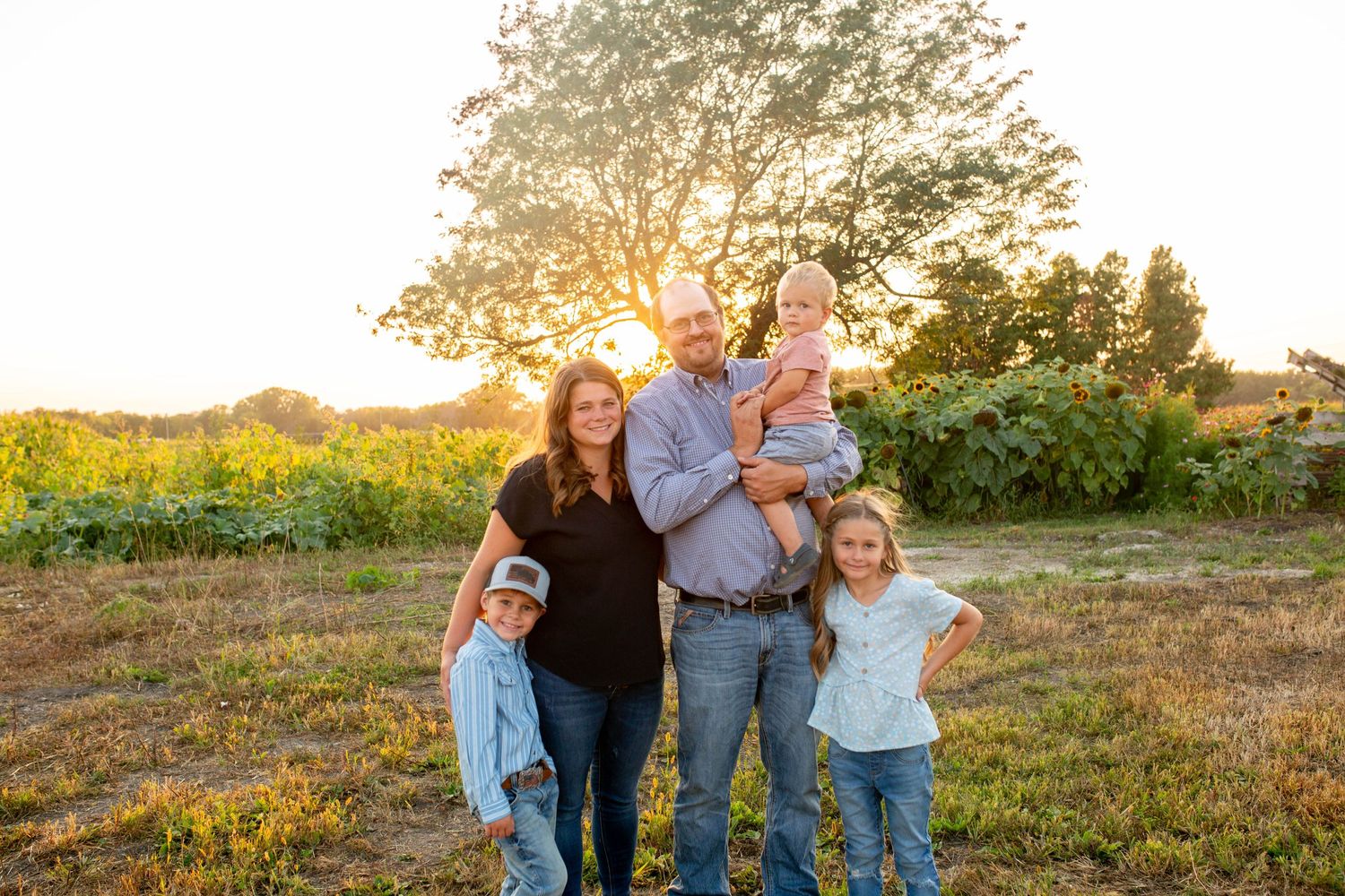 Iowa farm family posed at sunset in an open field, capturing warmth, love, and the beauty of rural life.
