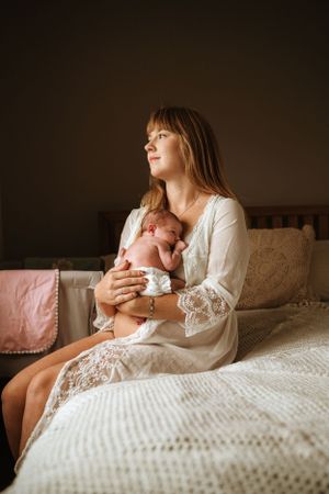 Intimate moments captured on a bed with soft white bedding and lace details.