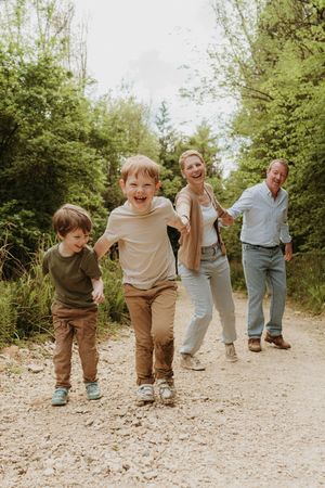 Playful family sequence walking and dancing on a gravel path surrounded by greenery.