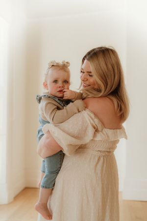 Mother and baby sharing joyful moments in white room with natural light.