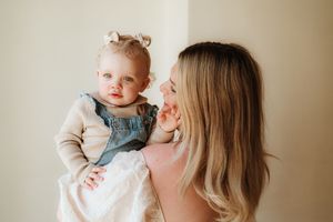 Tender parenting moment in soft beige tones against neutral background.
