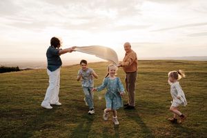 Group playing and dancing together in a grassy field during golden hour. Cleeve Common Cheltenham
