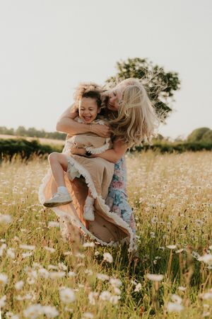 Joyful family playing together in a sun-drenched field of white wildflowers.