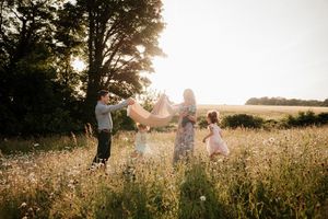 Scenic family photoshoot in a sun-drenched wildflower field during sunset.