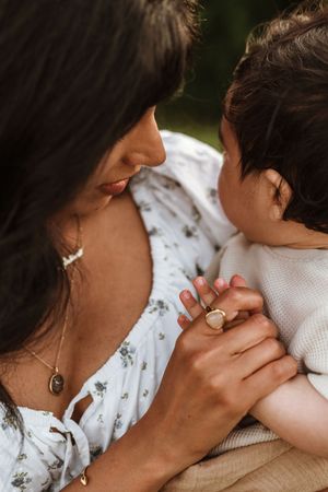 Close-up intimate moment showing hands and jewelry details against white clothing.