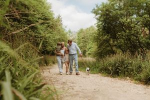 Family walking together on a nature trail surrounded by lush green foliage.