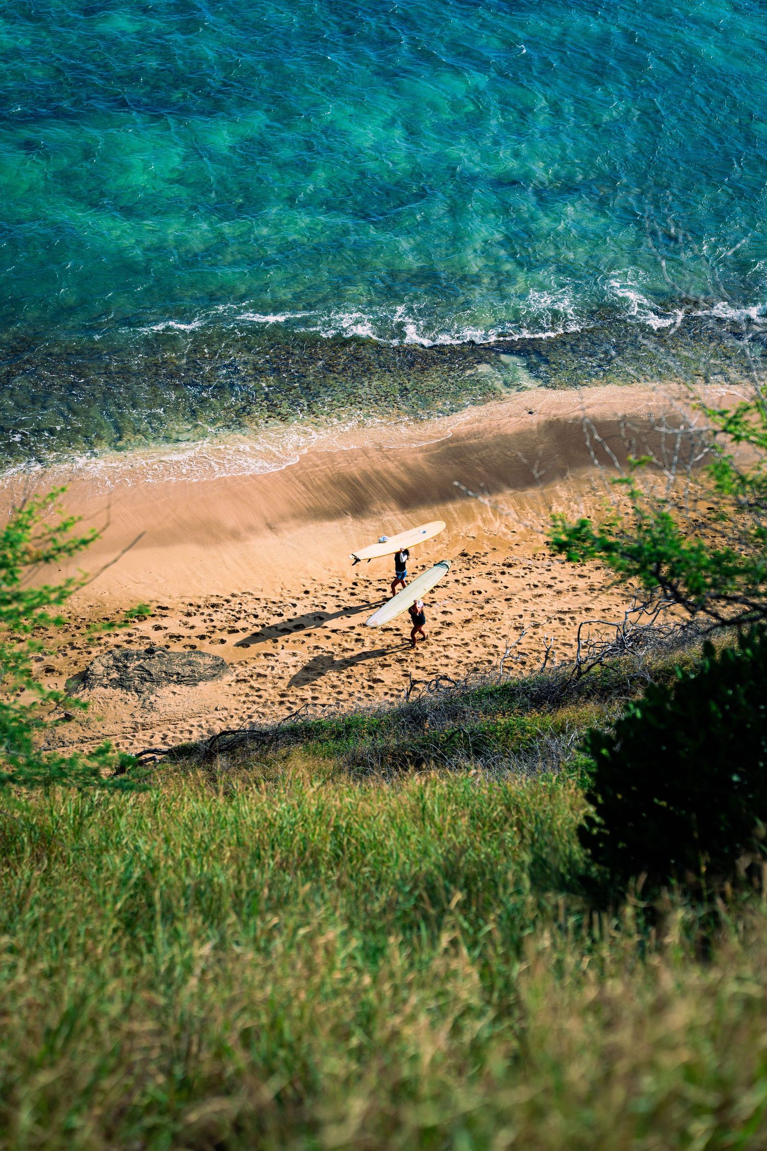Pristine sandy beach with turquoise ocean waves under blue sky with white clouds in Hawaii.