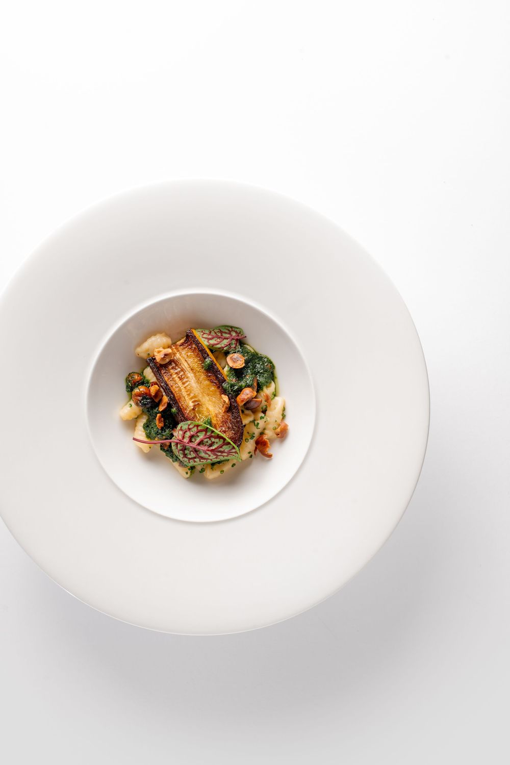 Four white plates of diminishing portion sizes showcase an elegant fine dining presentation technique.