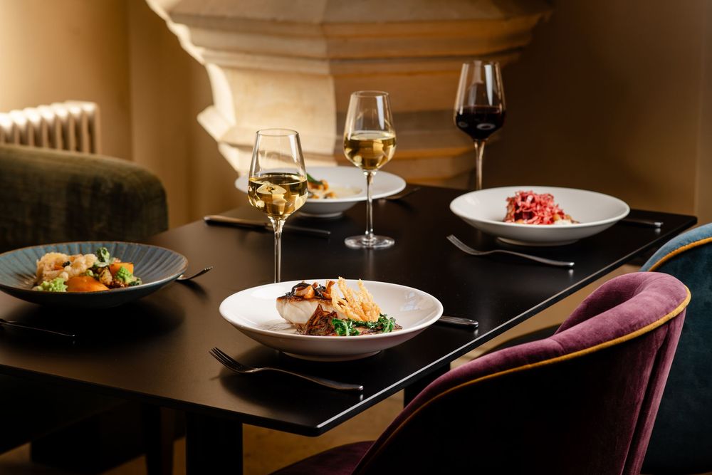 Elegant restaurant table setting with plated dishes and white wine glasses in warm ambient lighting.