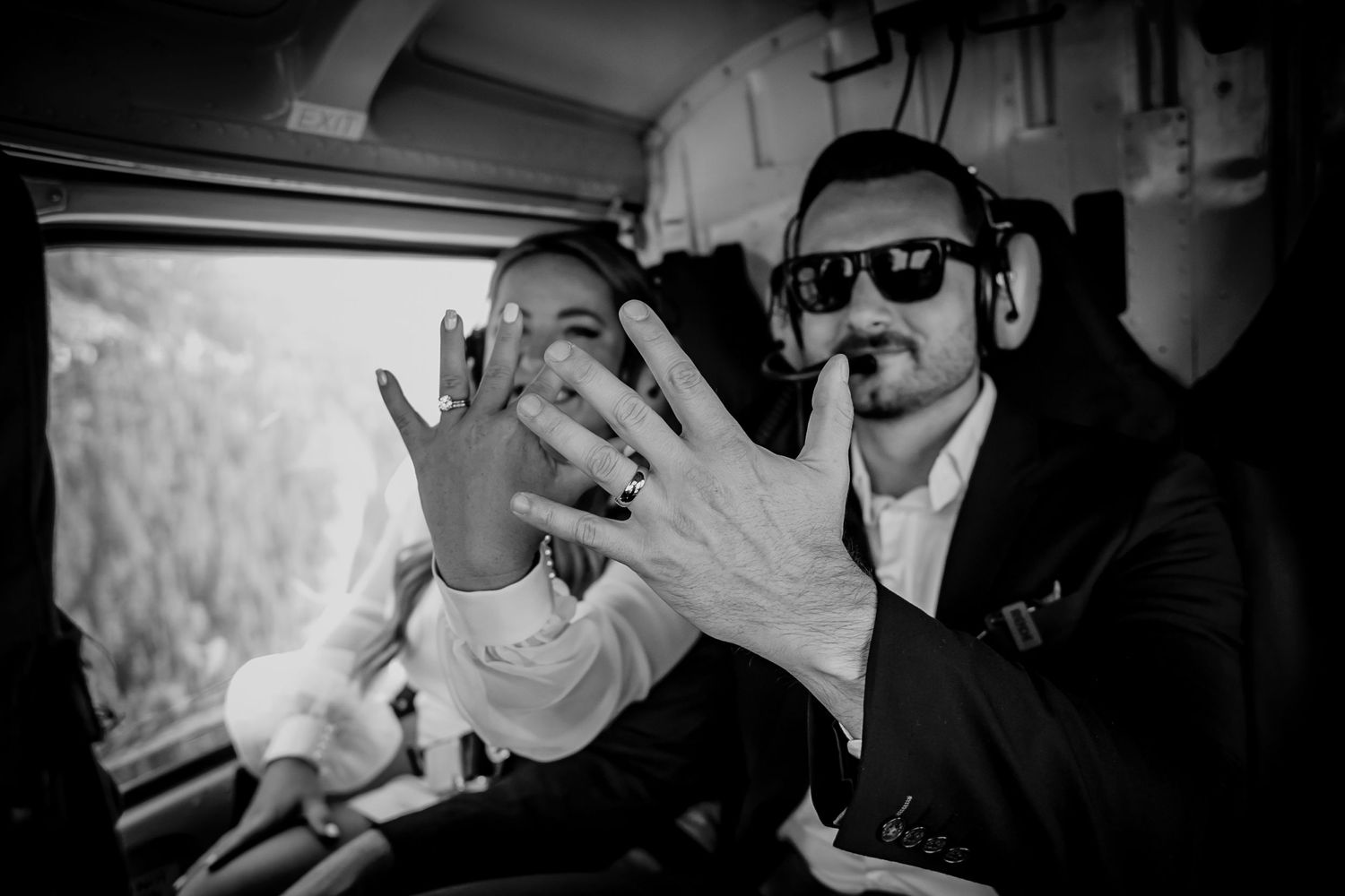 Black and white image of person in sunglasses gesturing with hands.