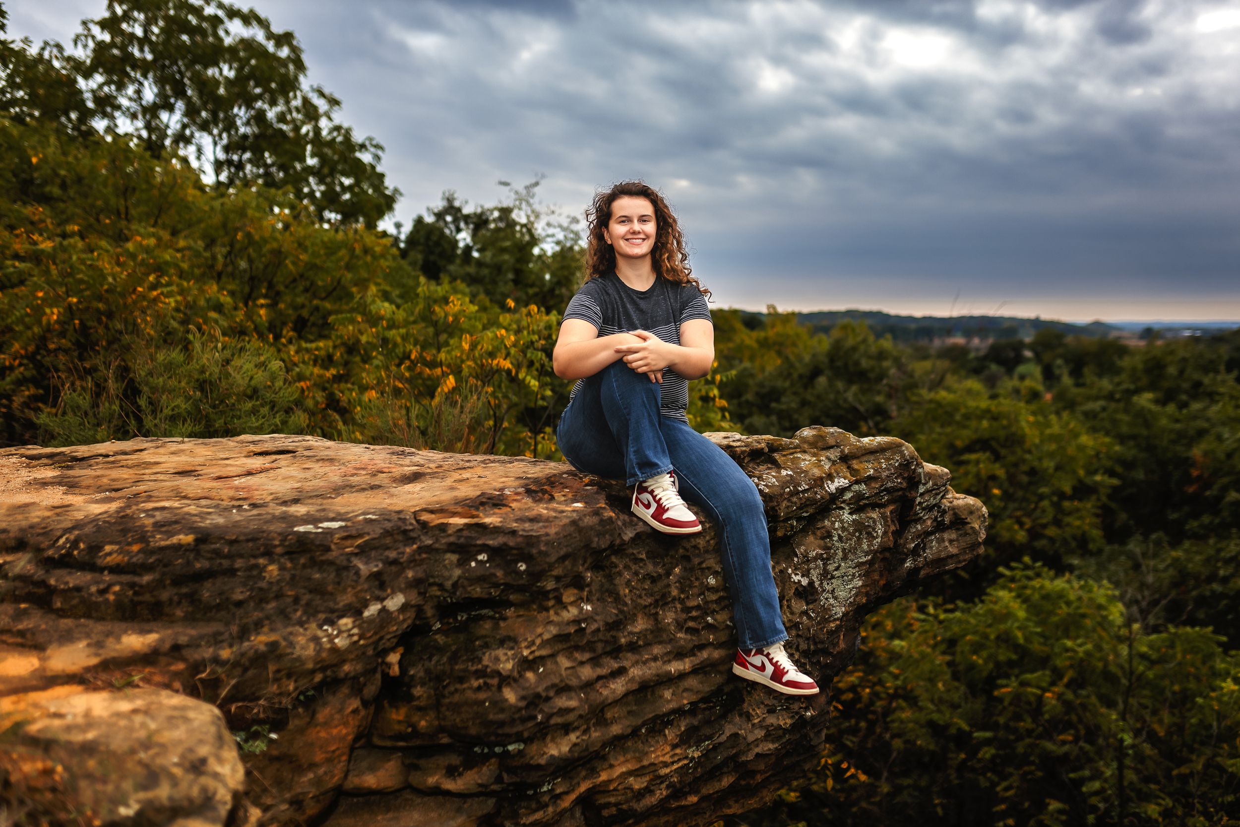 Casual portrait against dramatic cloudy sky with figure sitting on rocky cliff edge during golden hour.
Janesville, WI
Brodhead, WI