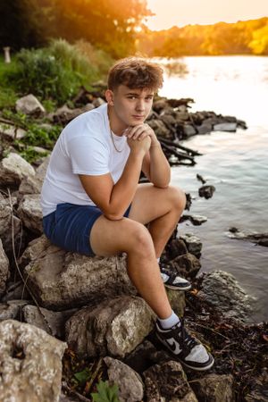 Person in white t-shirt and shorts sits thoughtfully on rocky lake shore at sunset.
Janesville, WI
Brodhead, WI