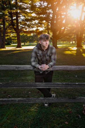 Person leans on wooden fence in park during golden hour sunset with sunbeams shining through trees. Janesville, WI
Brodhead, WI