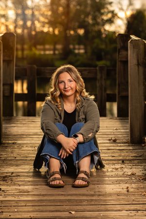 A casual autumn portrait session on a wooden dock during golden hour sunset.