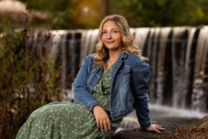 Professional outdoor portrait photography session near a cascading waterfall in autumn setting.