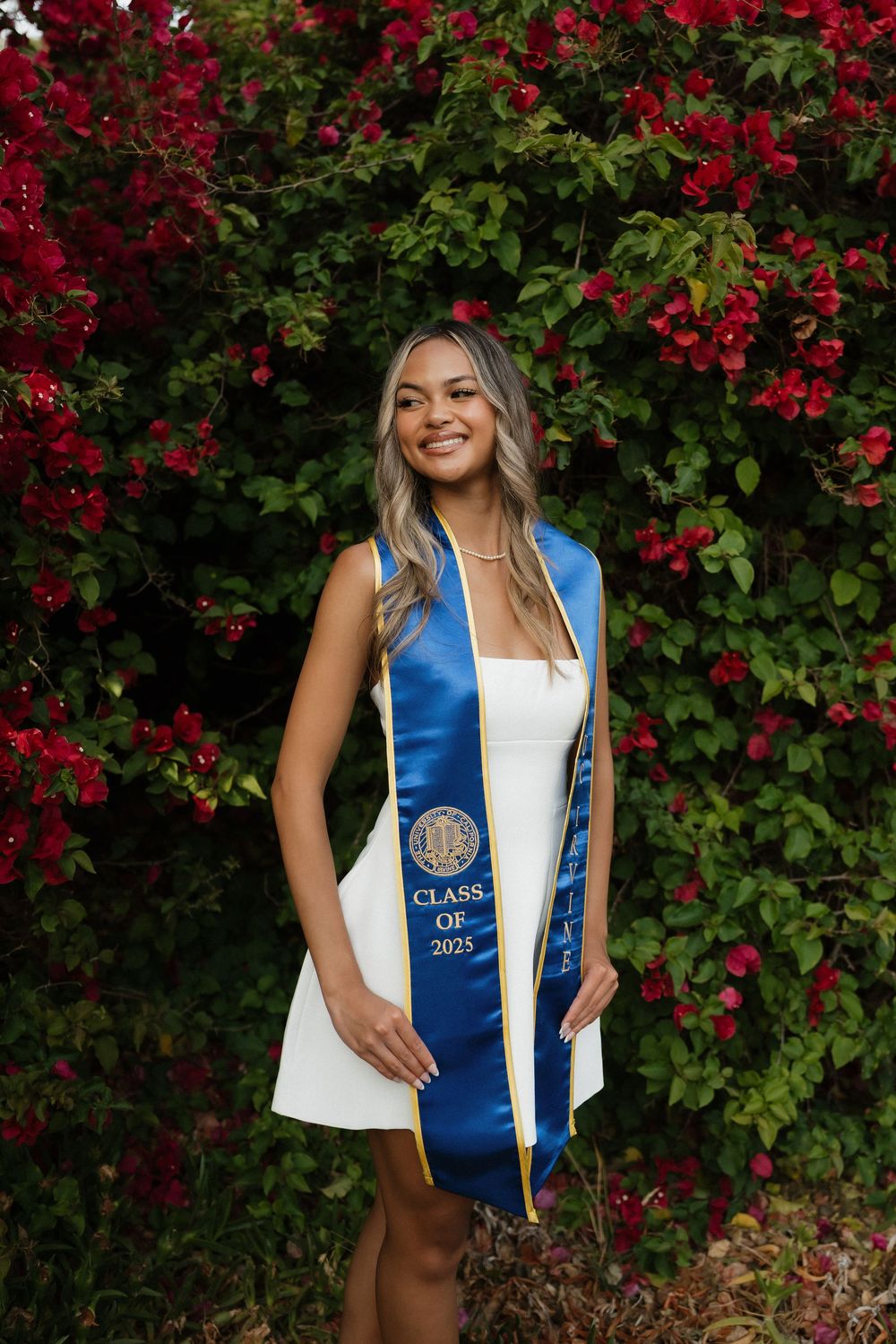 Graduation photos taken against a backdrop of vibrant red flowers and green foliage.