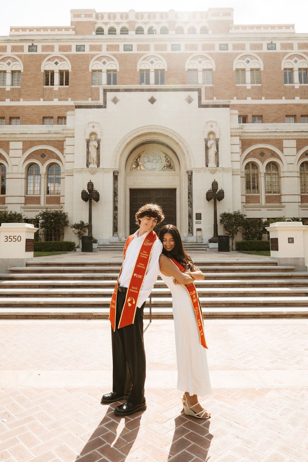 A series of graduation photos taken on steps of a grand brick university building with vintage warm tones.