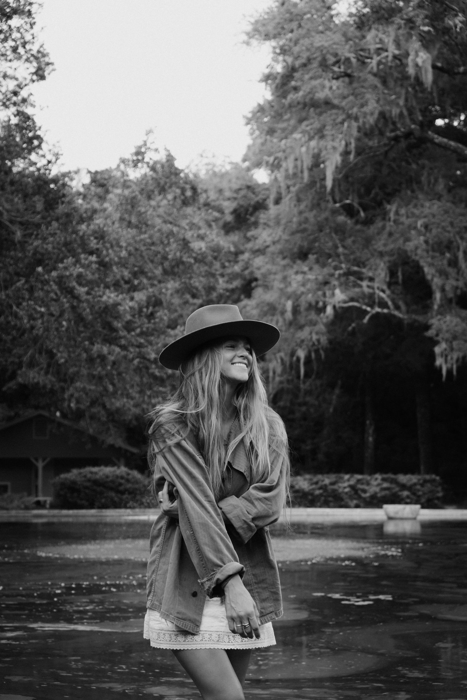 Person in a wide-brimmed hat dancing in a park with Spanish moss trees.