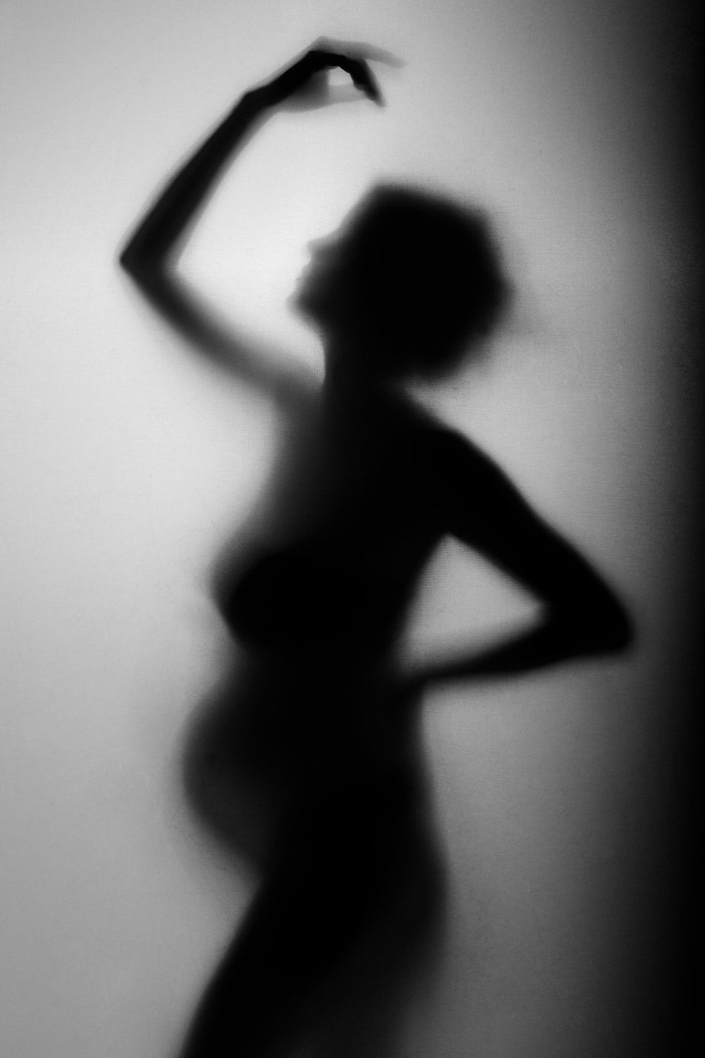 Artistic black and white silhouette of a dancer striking a graceful pose against a light background.Babybauch  Fotografie Hessen