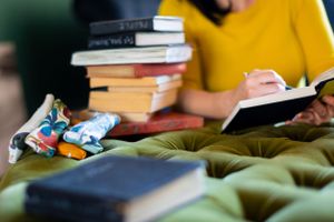 Stack of books with toy cars and notebook on quilted green surface.