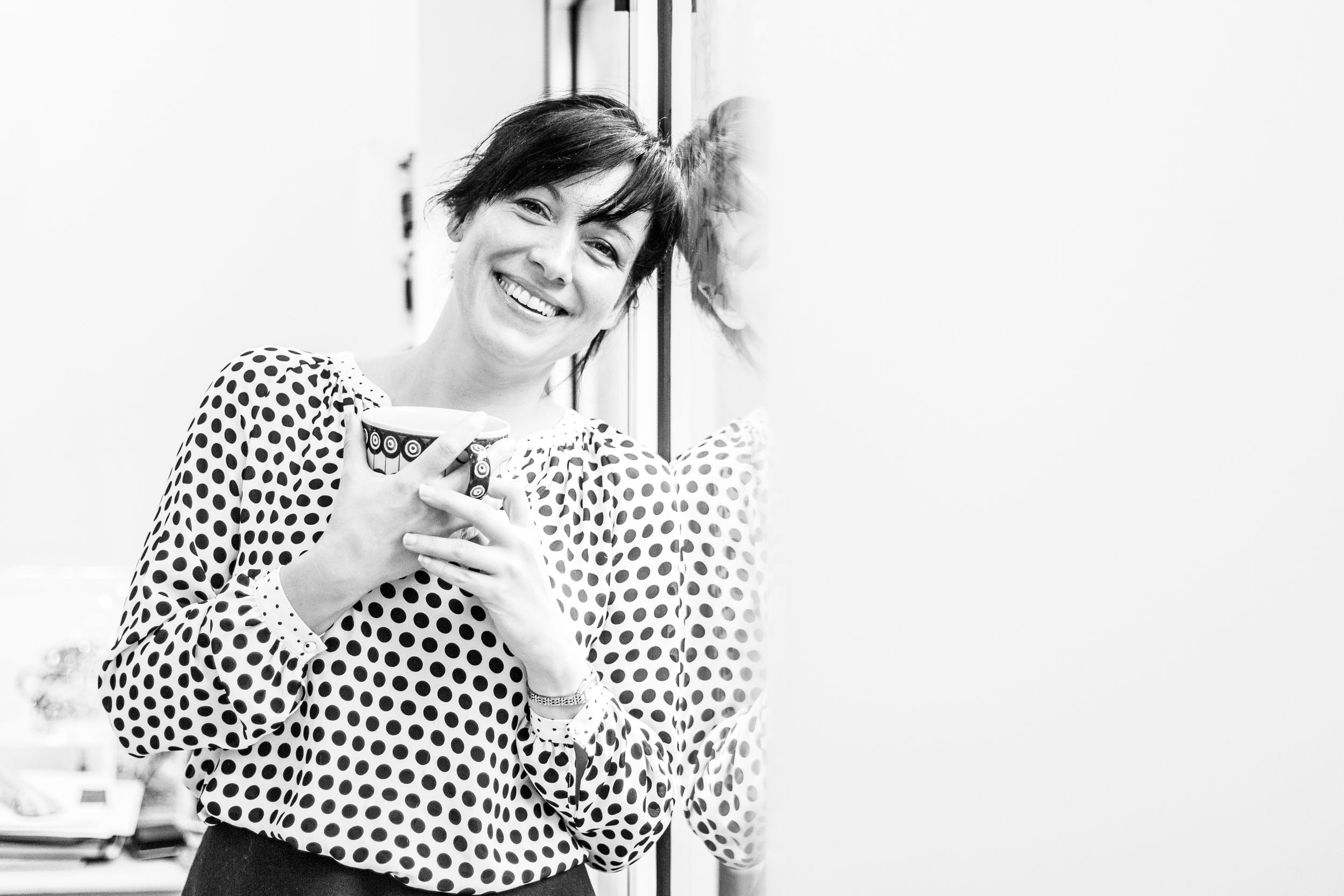 Black and white portrait of woman in polka dot top looking at mobile device.