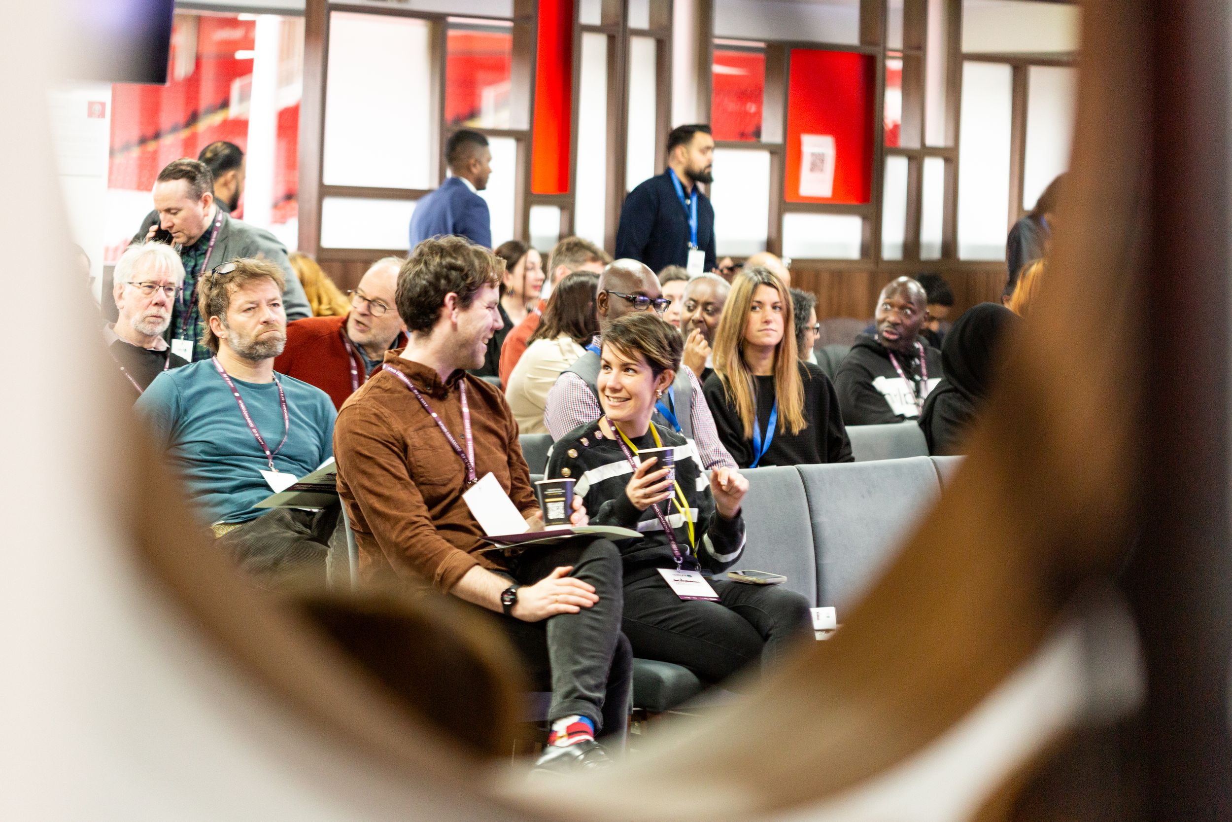 Crowd of attendees watching presentation in modern conference room setting.