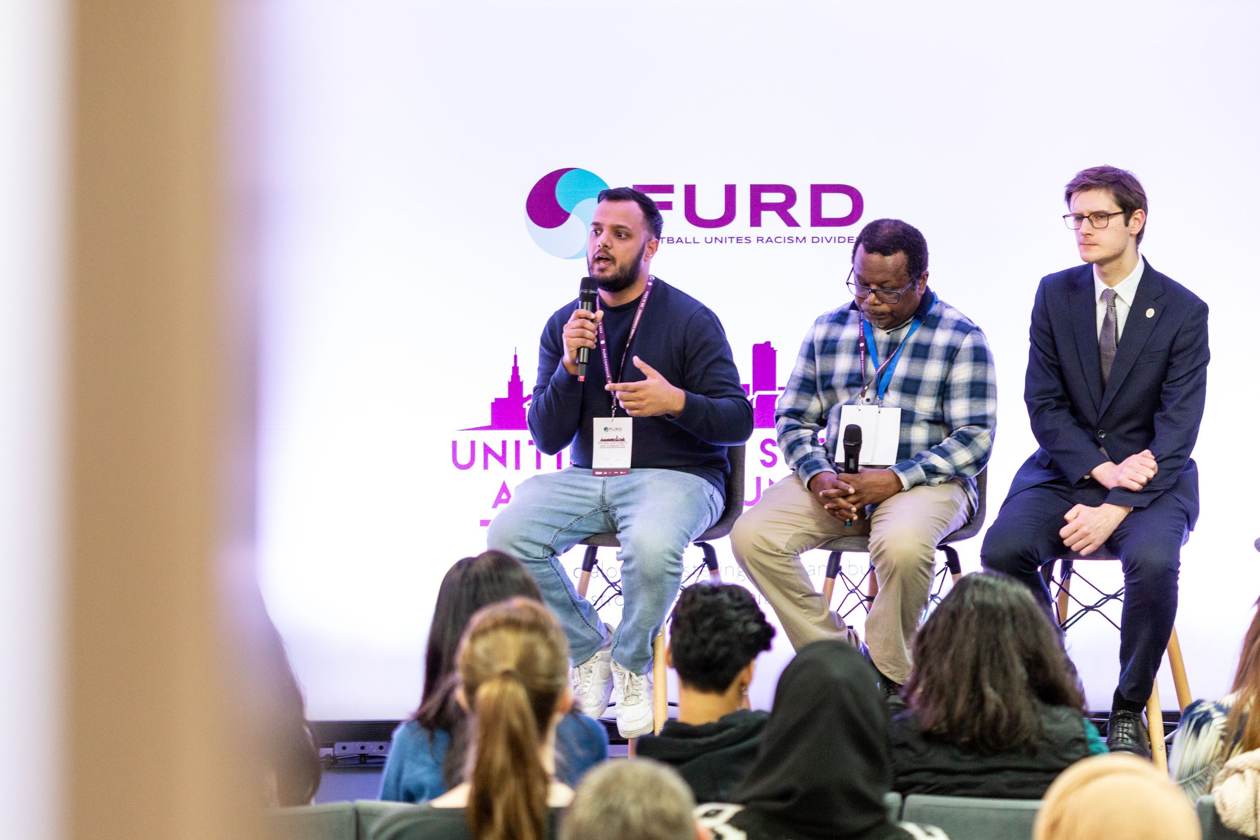 Panel discussion with speakers on stage at FURD conference event.