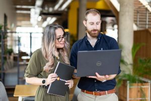 Two professionals reviewing work together on a laptop in a modern office space.