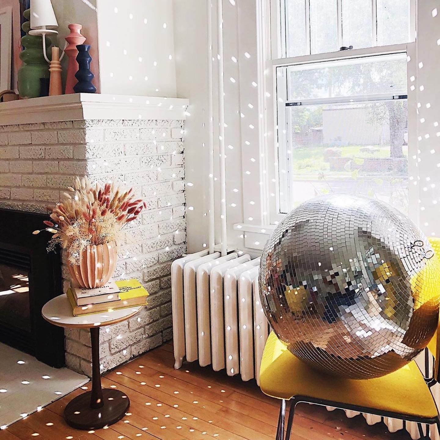 Disco ball reflecting light patterns onto white walls and radiators in a bright room.
