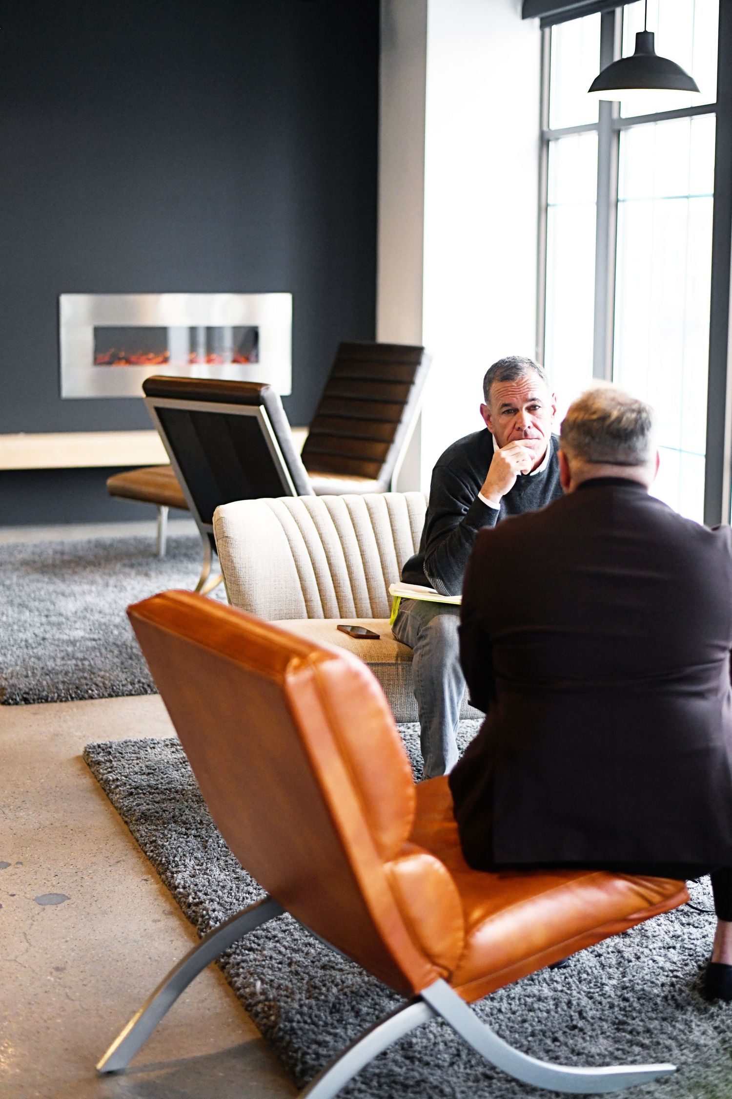 Modern lounge area with leather chairs and fireplace featuring business meeting setup.